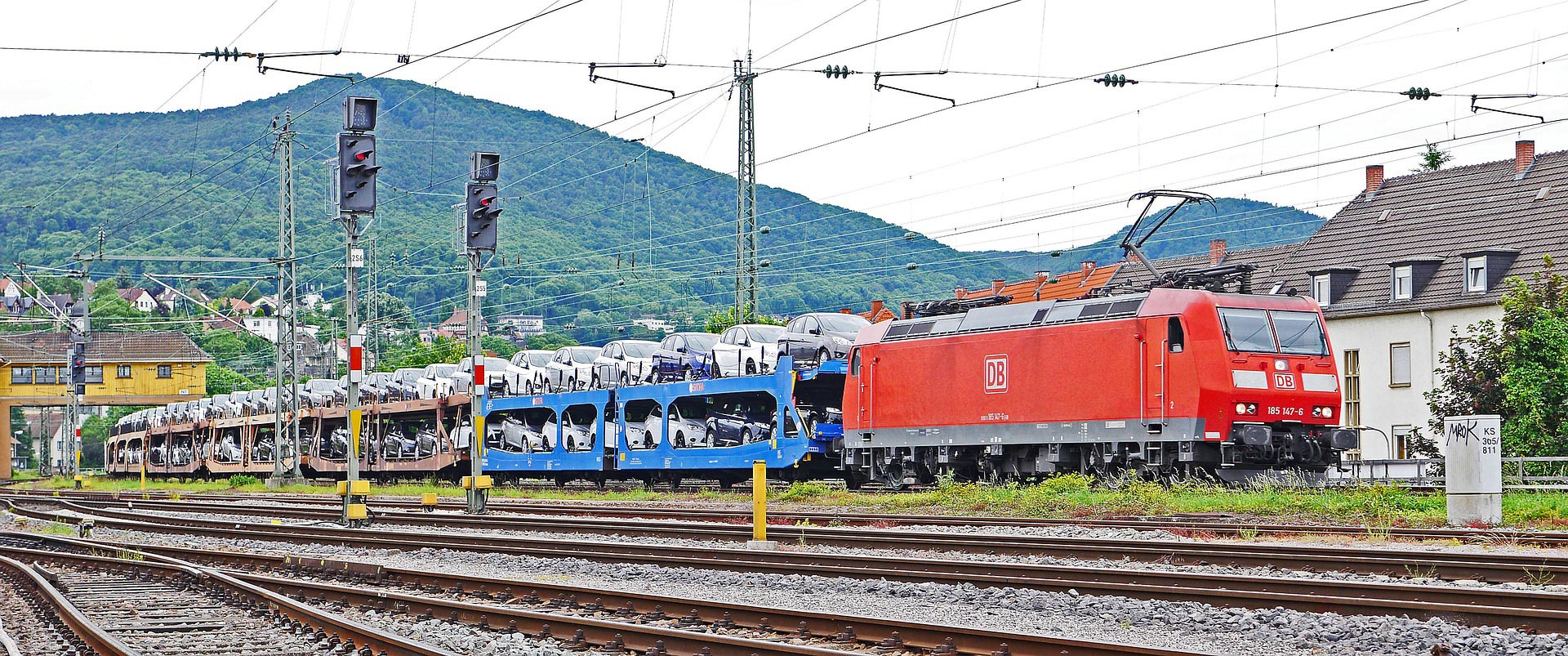 eisenbahnversicherung-gueterzug Rote Elektrolokomotive mit Güterwagen für den Autotransport